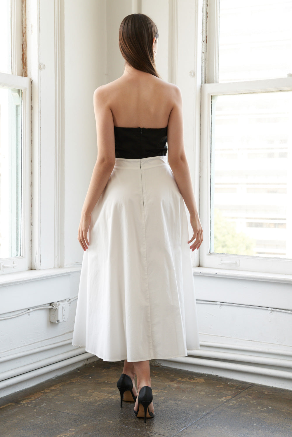 A solid woven midi dress featuring strapless top with bow, full skirt and back zipper closure