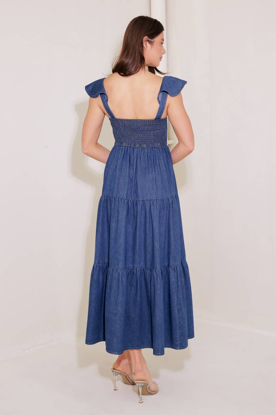 A washed denim midi dress featuring square neckline, ruffle sleeve, button down, tiered skirt and smocked back bodice