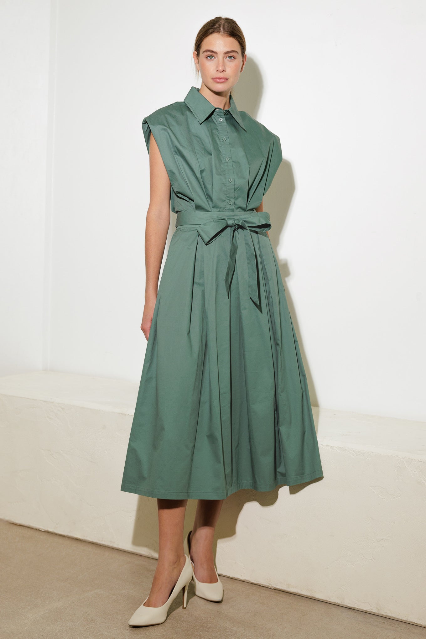 A solid woven midi dress featuring shirt collar, button down, drop shoulder, pleated skirt and self sash tie