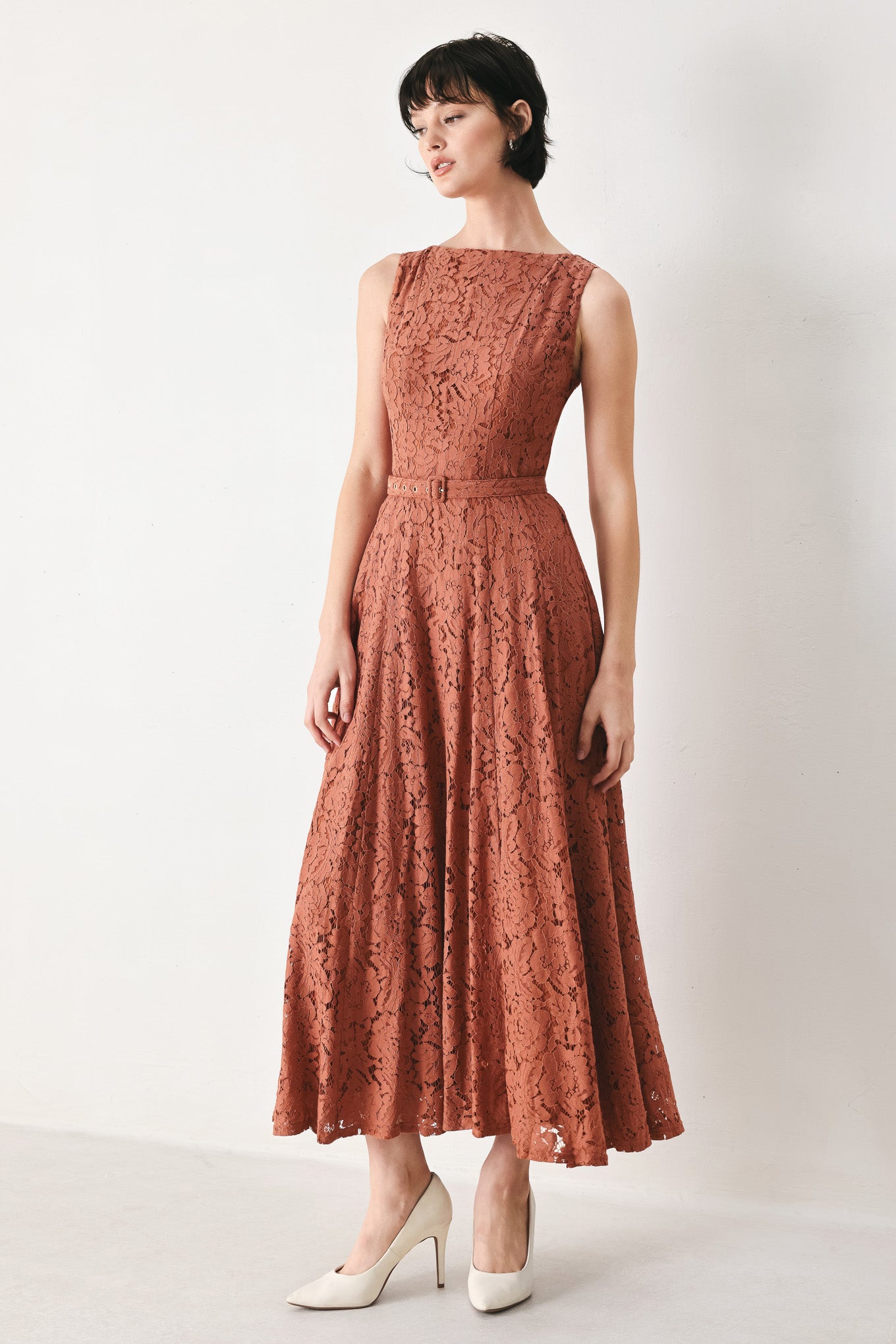 Woman wearing a rust colored lace midi dress featuring wide neckline, sleeveless, self belt, full circle skirt and back zipper closure | FREEMARKET