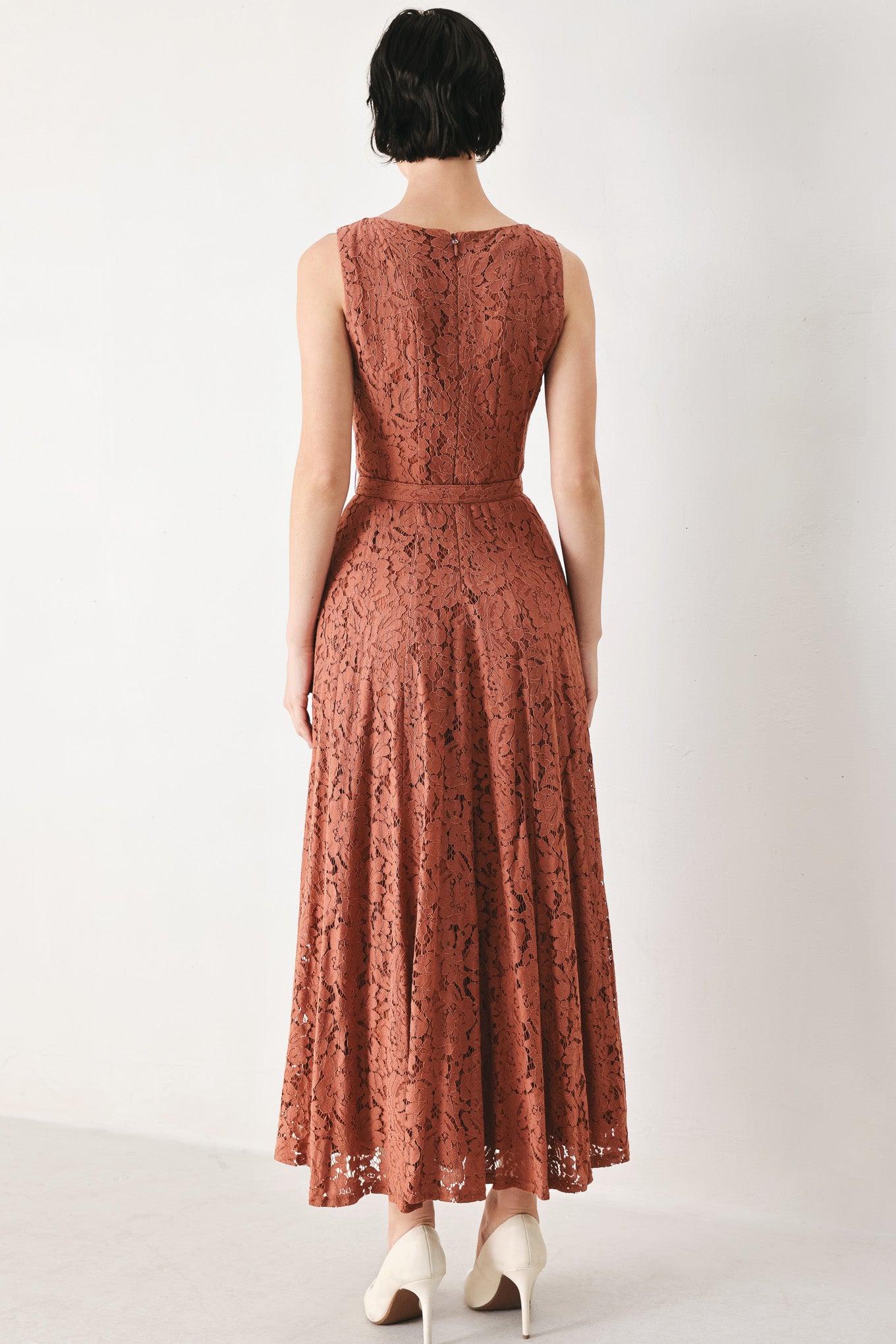 Woman wearing a rust colored lace midi dress featuring wide neckline, sleeveless, self belt, full circle skirt and back zipper closure | FREEMARKET