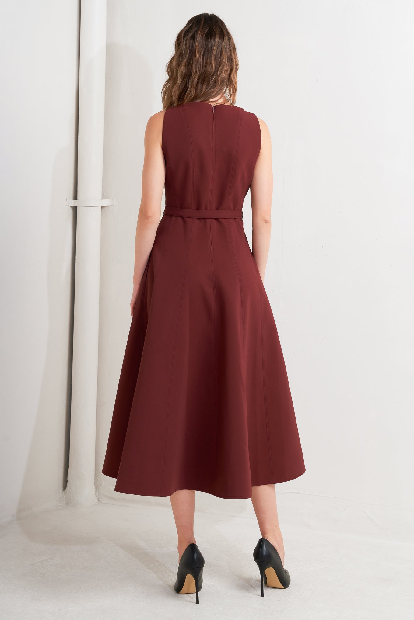 A solid woven midi dress featuring boat neckline, sleeveless, full skirt, self belt, side pocket and full skirt
