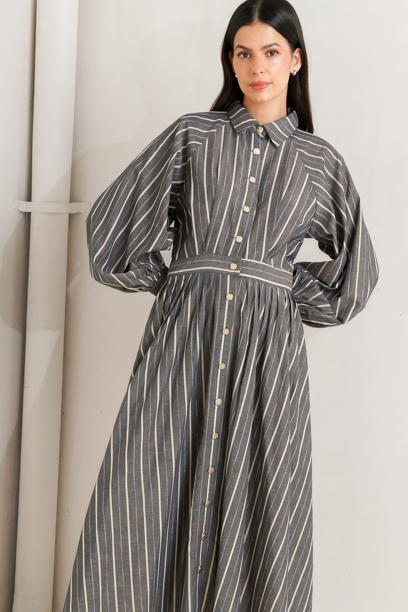 Woman wearing a striped dress standing against a white wall - Flying Tomato