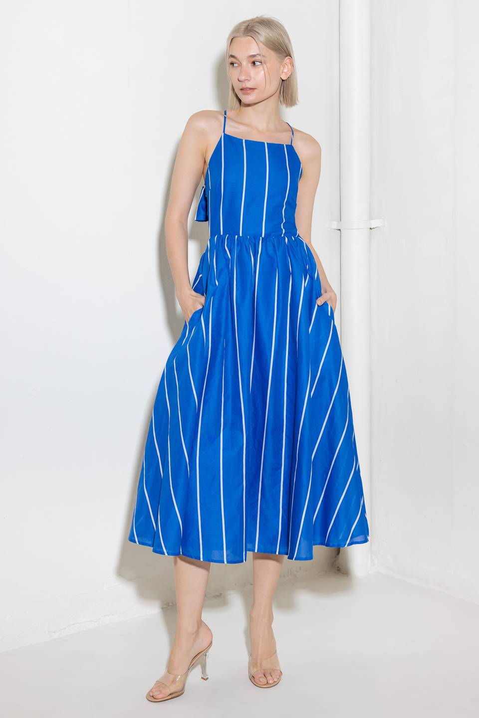 A blue and white striped woven midi dress featuring bib neckline, full skirt and bare back with strap and tie closure.