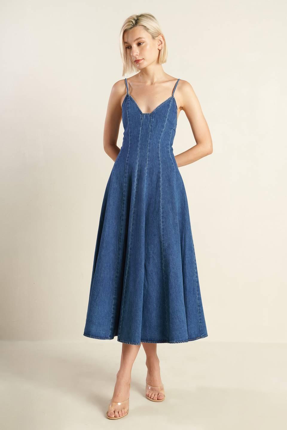A washed denim dress featuring cami top with straps, fitted waist, side pockets, full skirt and back zipper closure