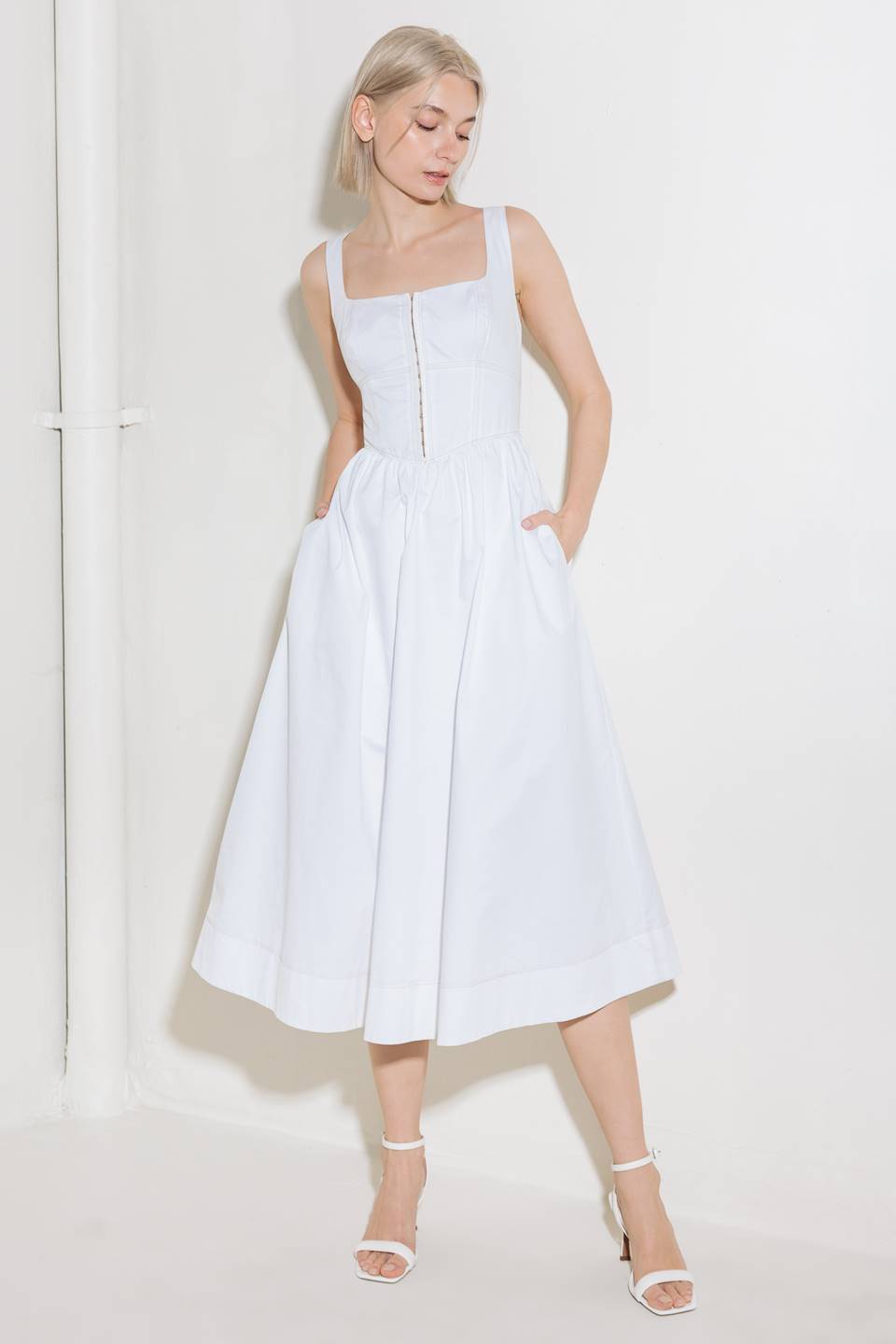 A solid woven midi dress featuring square neckline, sleeveless, front hook and  eye closure, full skirt and back zipper closure.