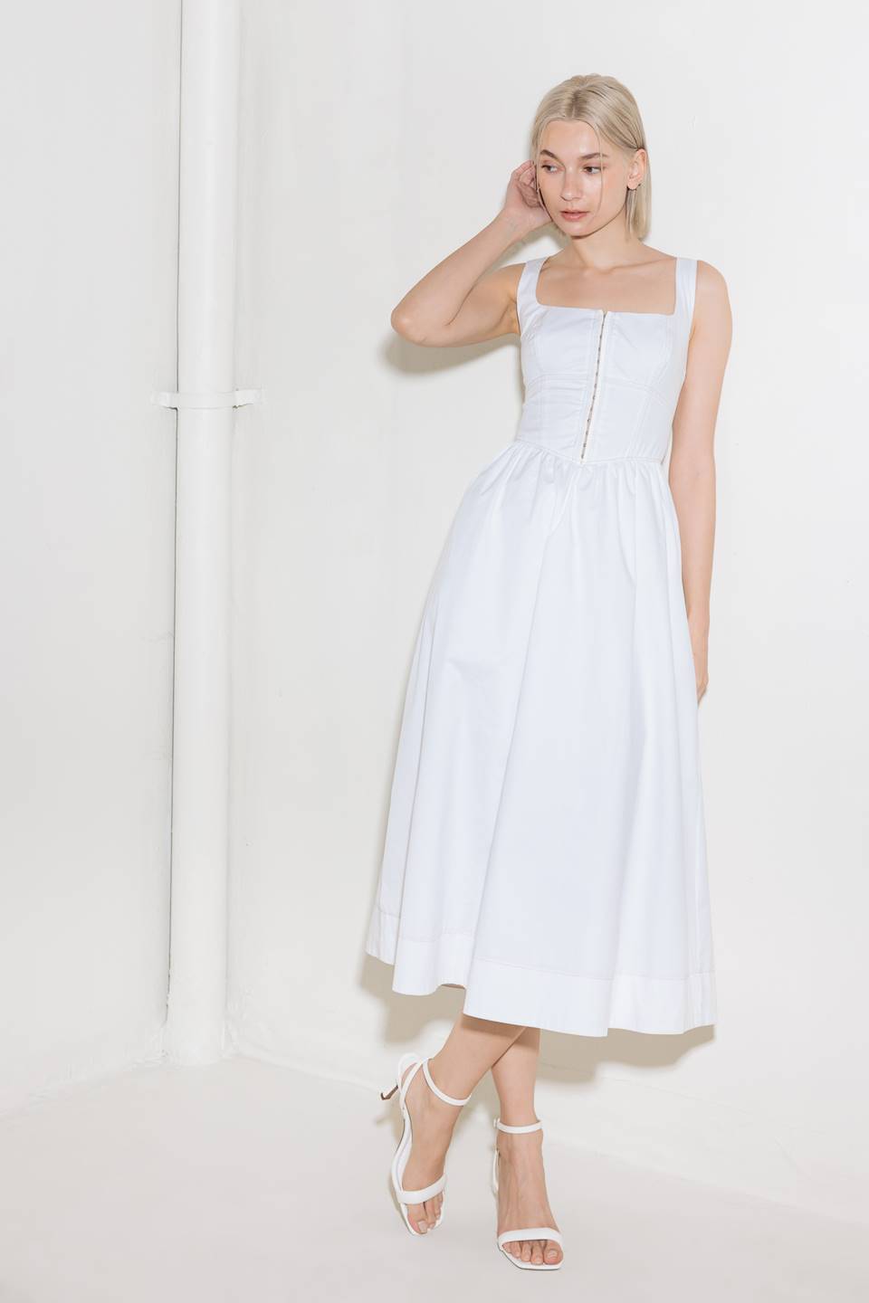 A solid woven midi dress featuring square neckline, sleeveless, front hook and eye closure, full skirt and back zipper closure.