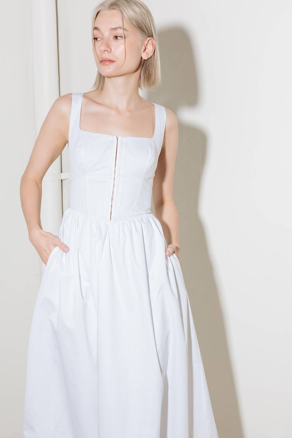 A solid woven midi dress featuring square neckline, sleeveless, front hook and eye closure, full skirt and back zipper closure.