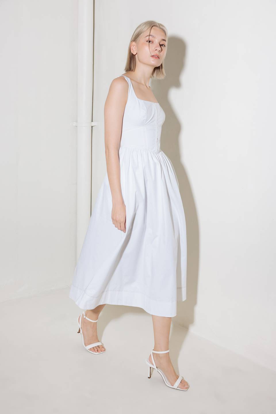 A solid woven midi dress featuring square neckline, sleeveless, front hook and eye closure, full skirt and back zipper closure.