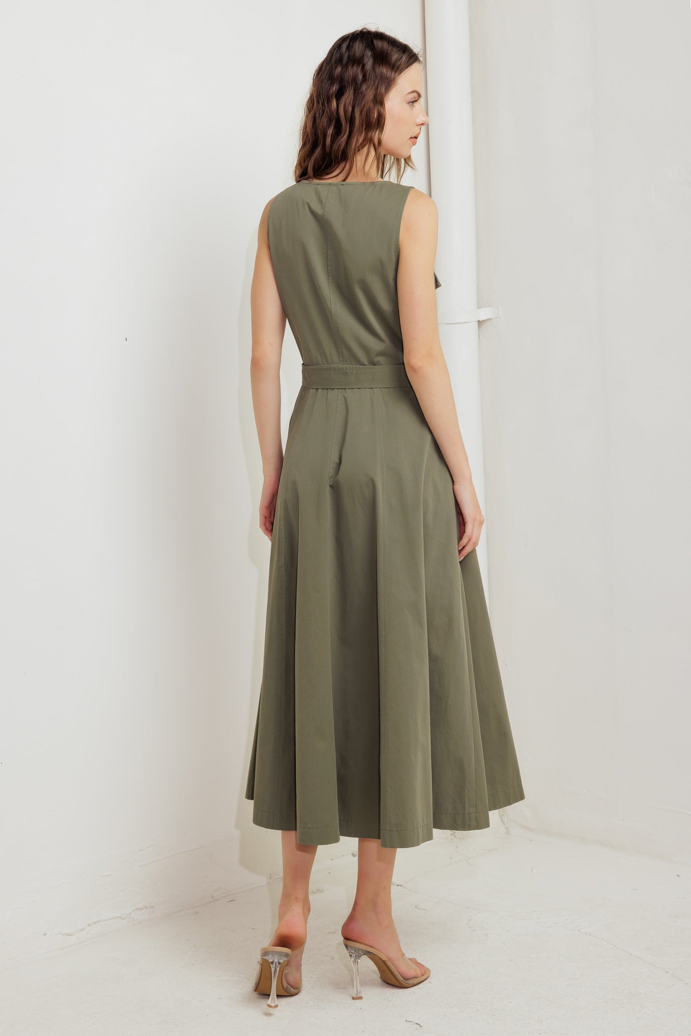 A solid woven midi dress featuring square neckline, sleeveless, front pockets, zipper closure, self belt and circle skirt