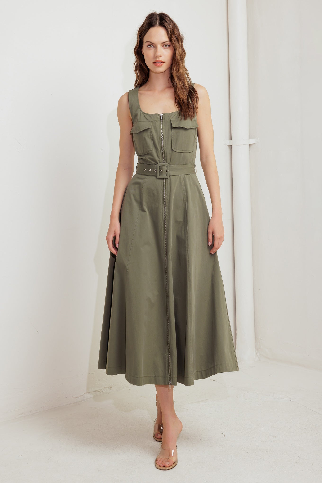 A solid woven midi dress featuring square neckline, sleeveless, front pockets, zipper closure, self belt and circle skirt