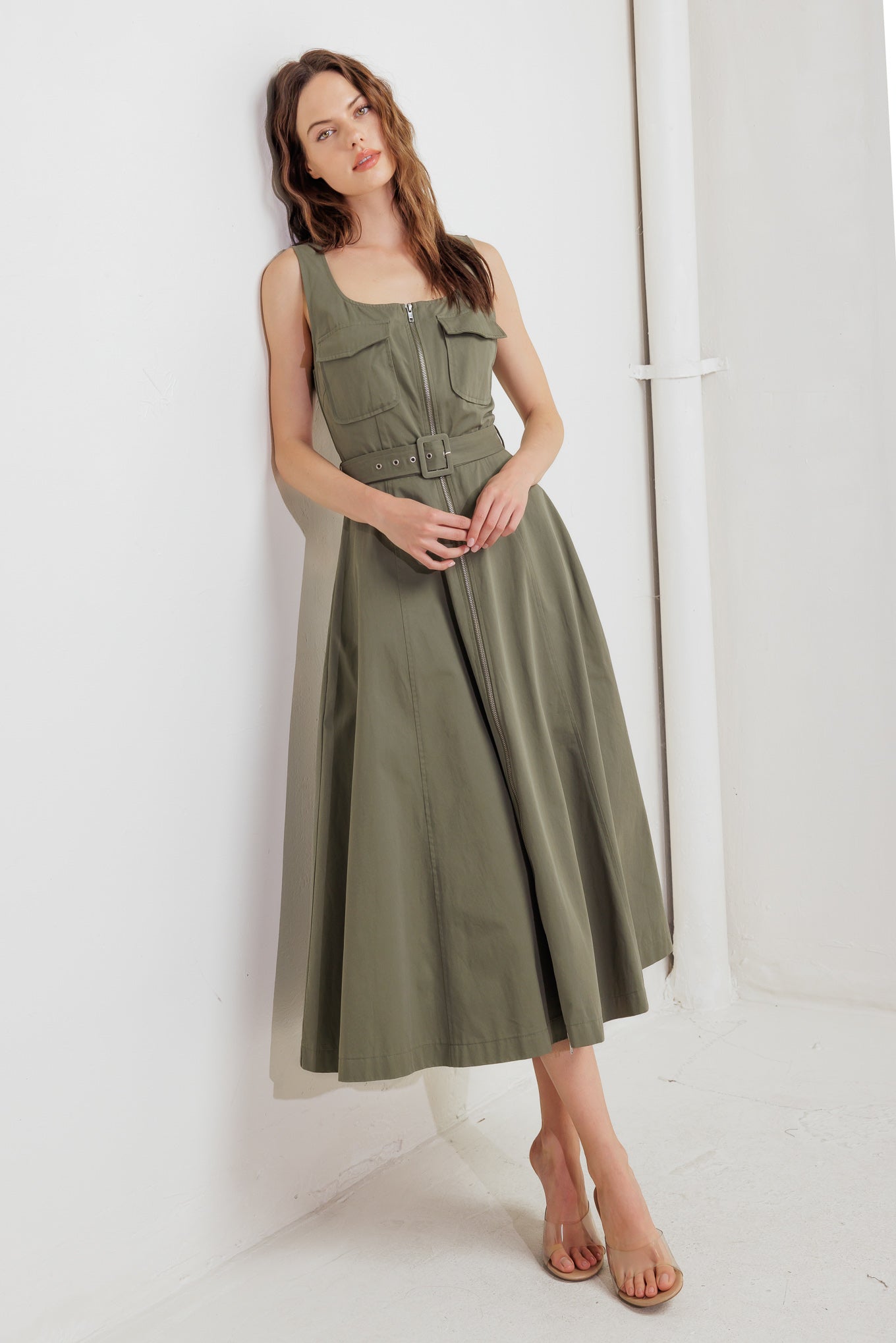 A solid woven midi dress featuring square neckline, sleeveless, front pockets, zipper closure, self belt and circle skirt