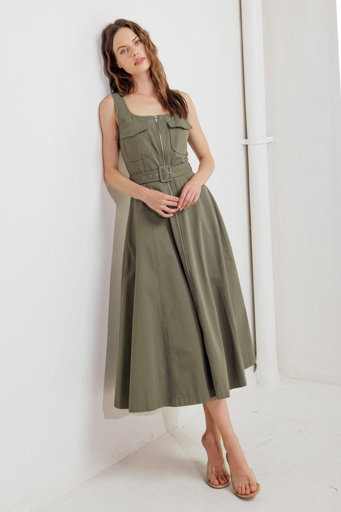 A solid woven midi dress featuring square neckline, sleeveless, front pockets, zipper closure, self belt and circle skirt