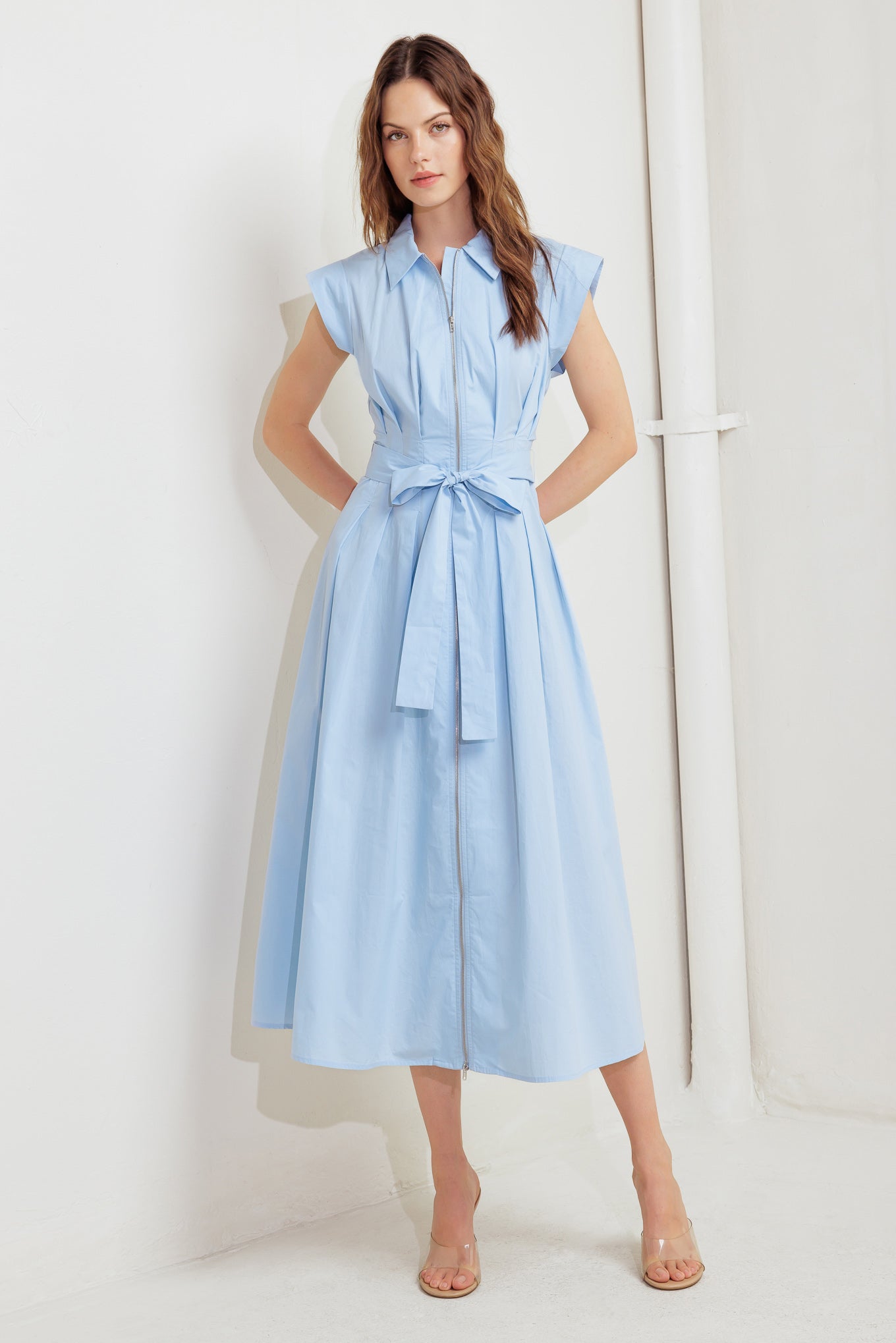 A solid woven midi dress featuring collar, short sleeve, front zipper closure and self sash tie