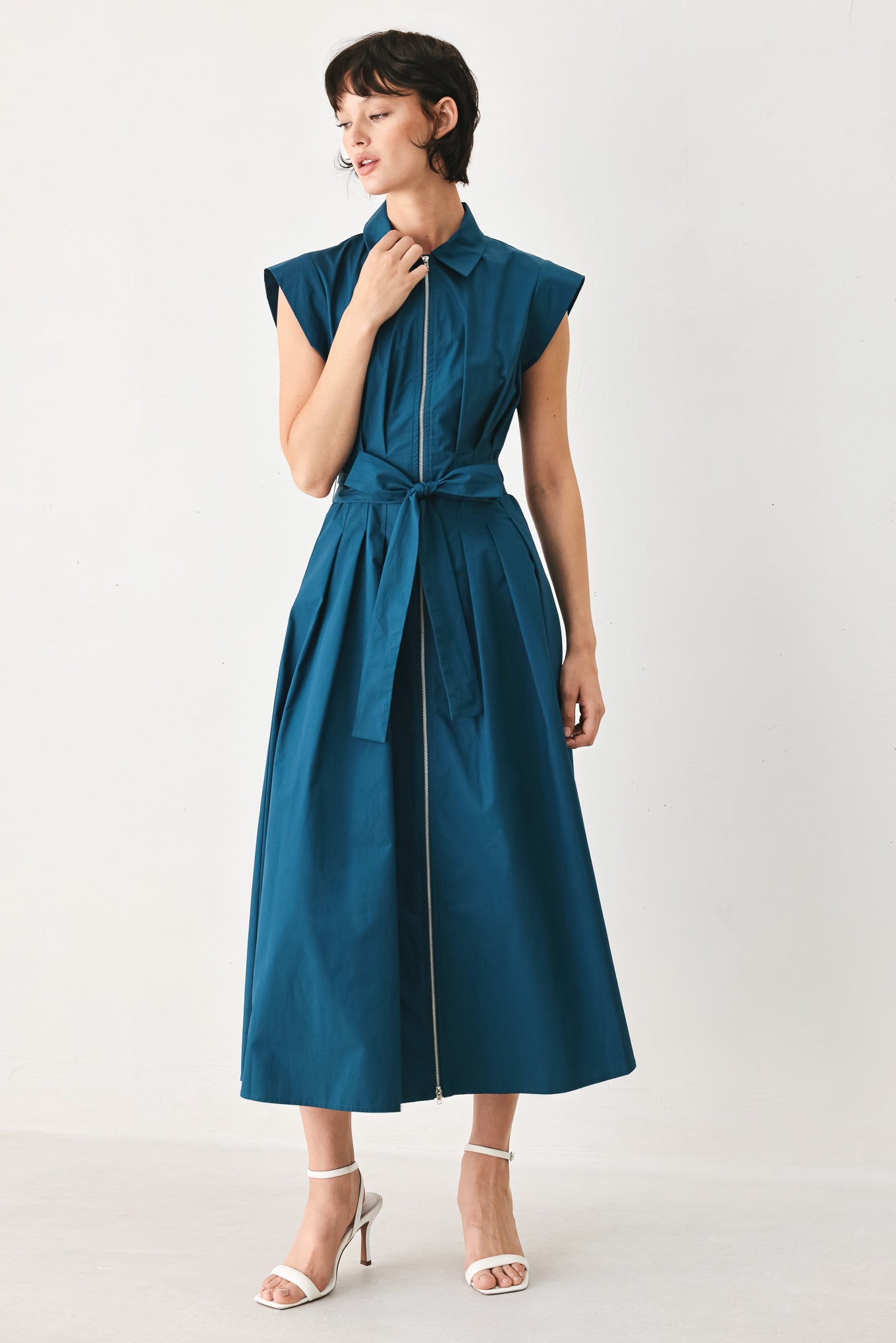 Woman wearing a teal midi dress featuring collar, short sleeve, front zipper closure and self sash tie | FREEMARKET