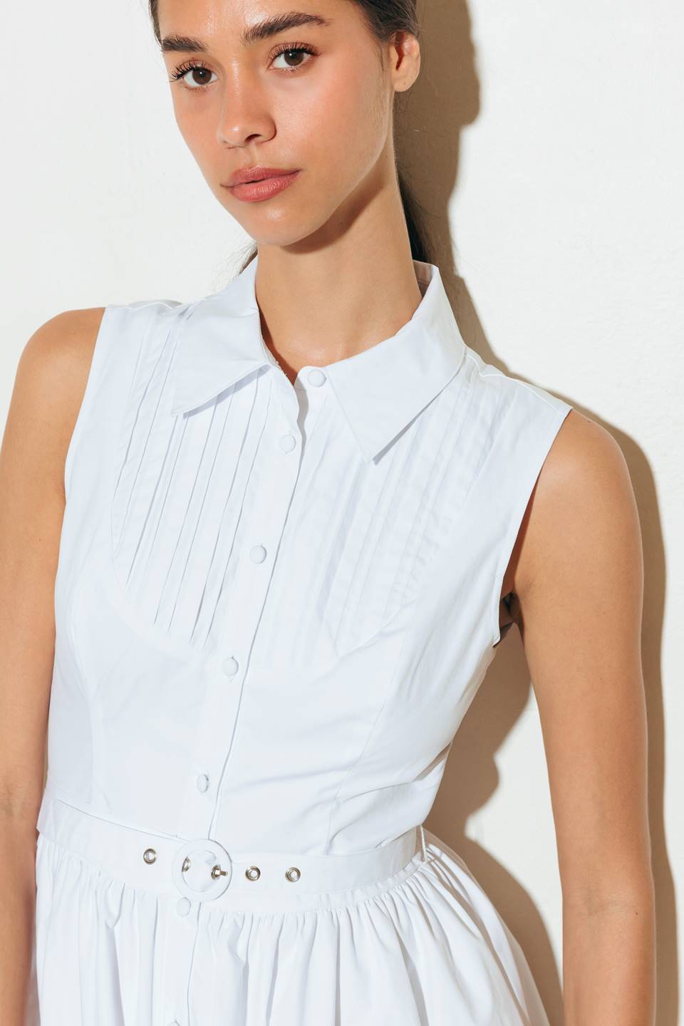 A solid white, woven midi dress featuring collar, front button down, pintuck bib, sleeveless, self belt and full skirt.