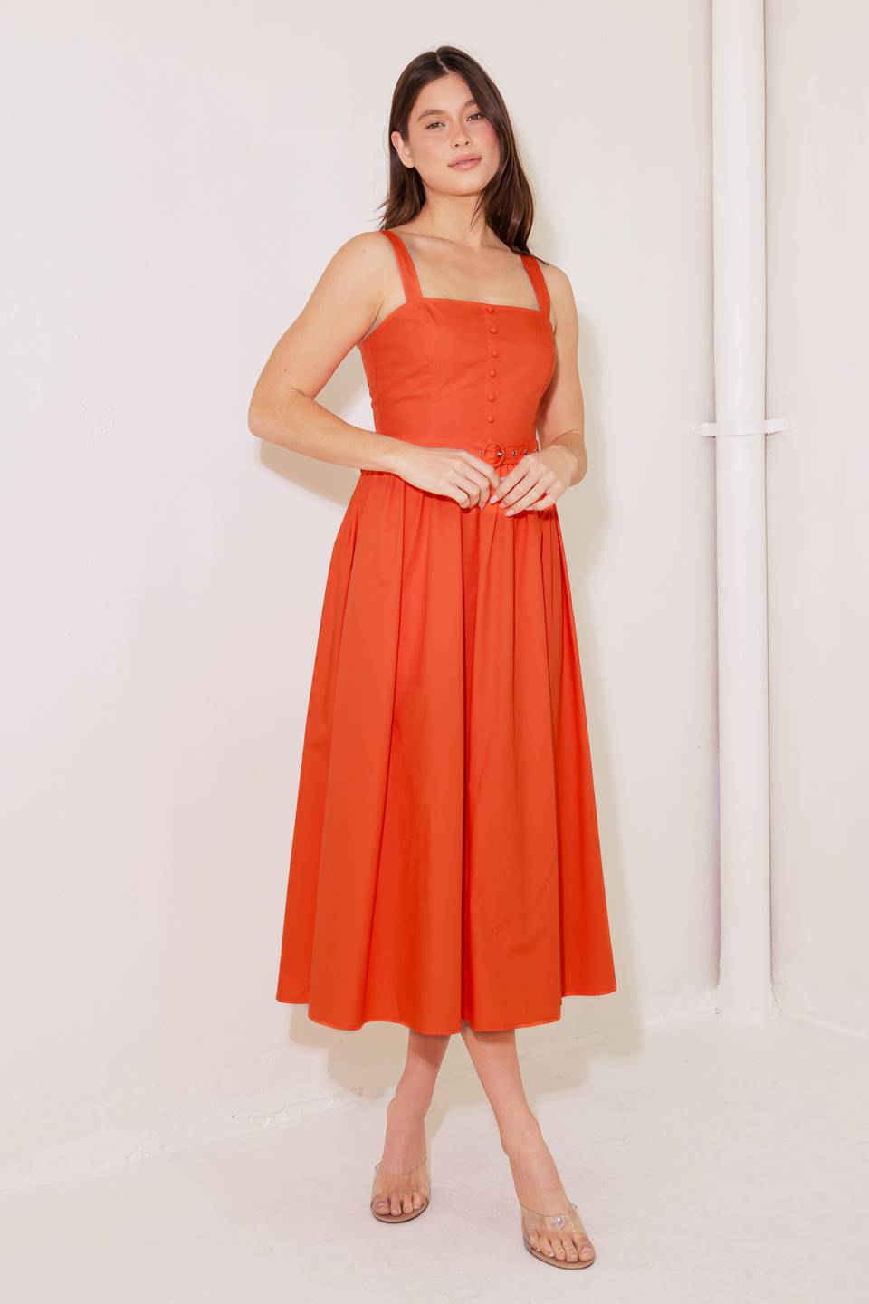 A solid red woven midi dress featuring straight neckline, straps, front bodice button down, self belt and back zipper closure