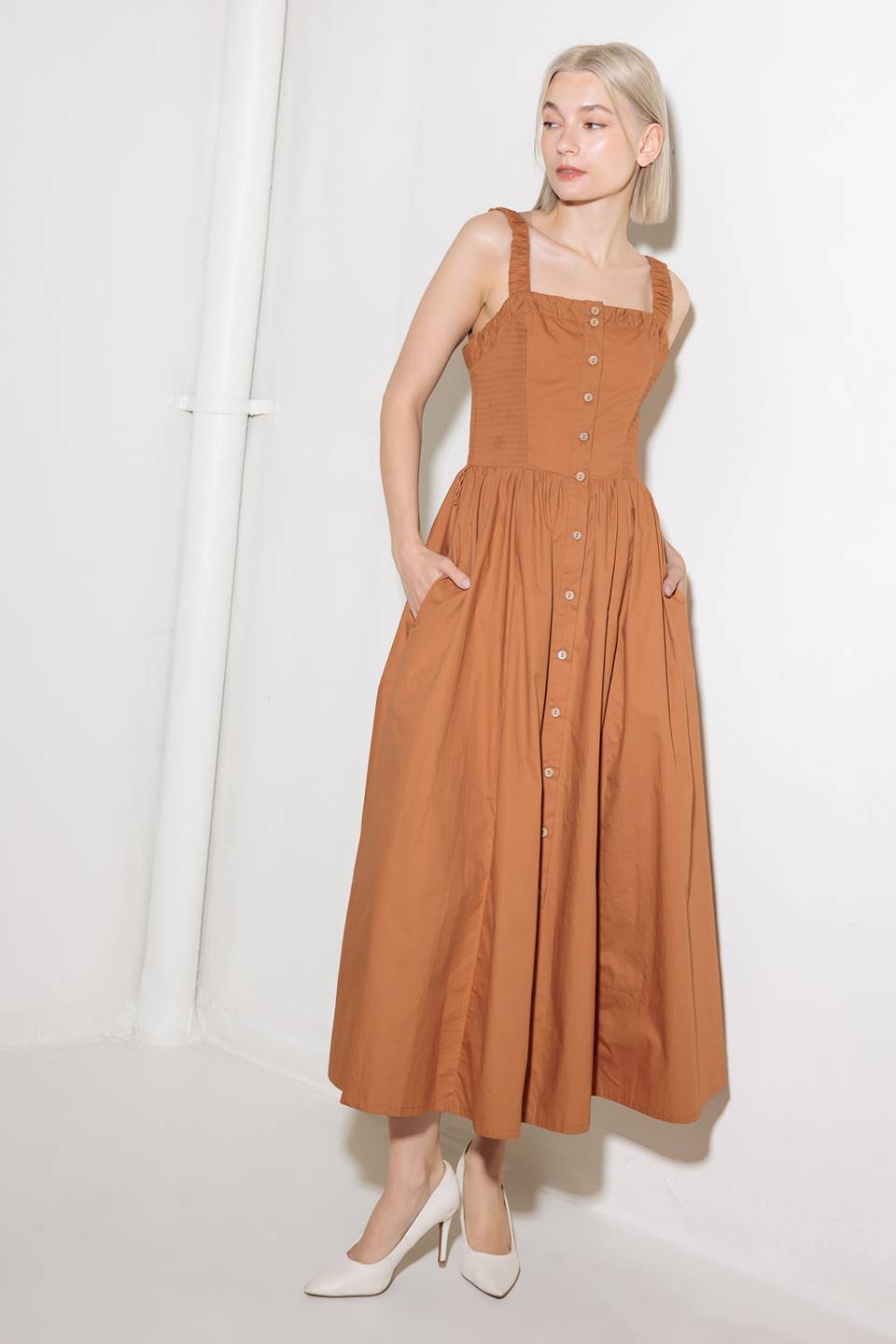 A solid woven midi dress featuring straight neckline, straps, side smocking, self sash tie and full skirt.