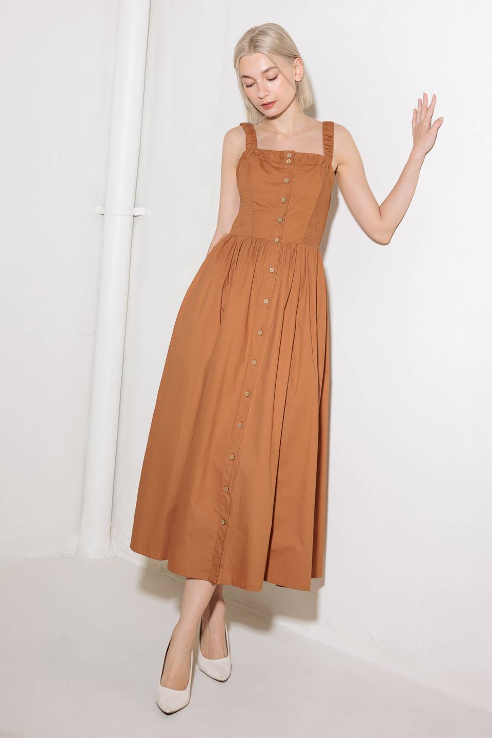 A solid woven midi dress featuring straight neckline, straps, side smocking, self sash tie and full skirt.