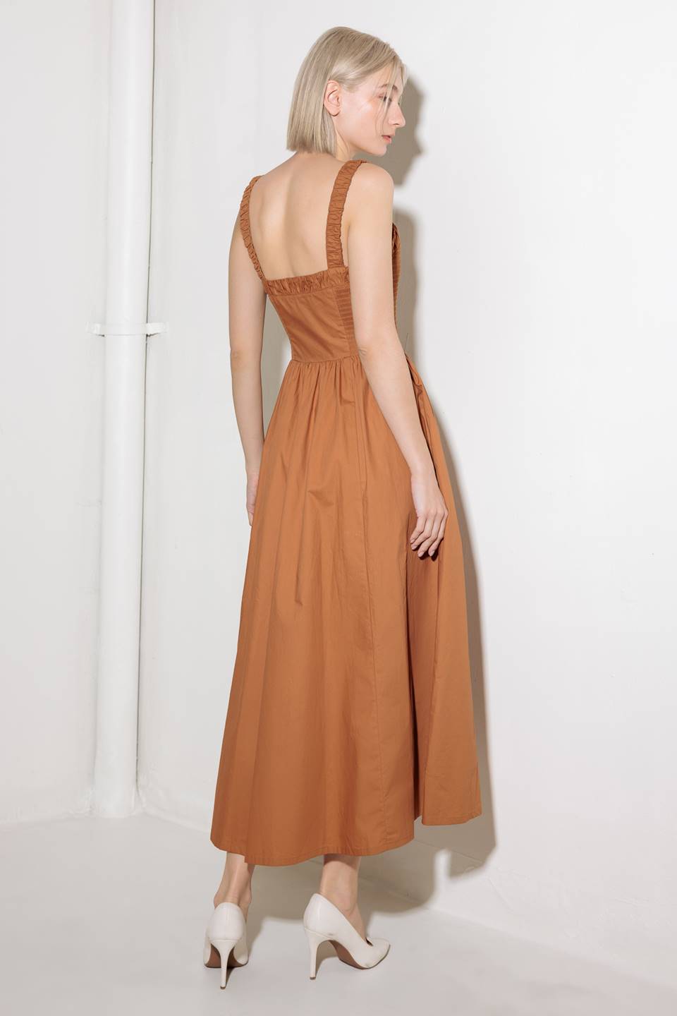 A solid woven midi dress featuring straight neckline, straps, side smocking, self sash tie and full skirt.
