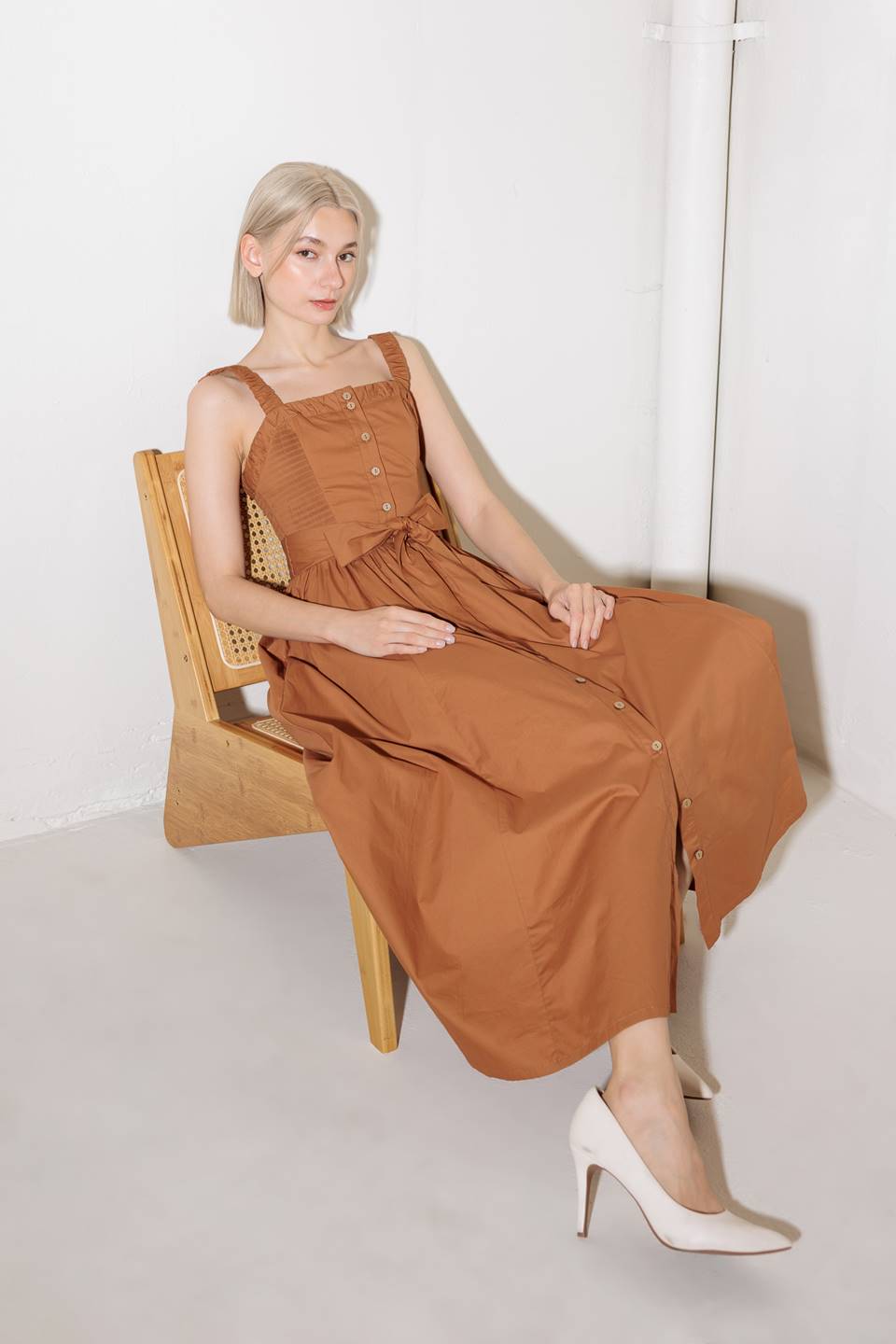 A solid woven midi dress featuring straight neckline, straps, side smocking, self sash tie and full skirt.