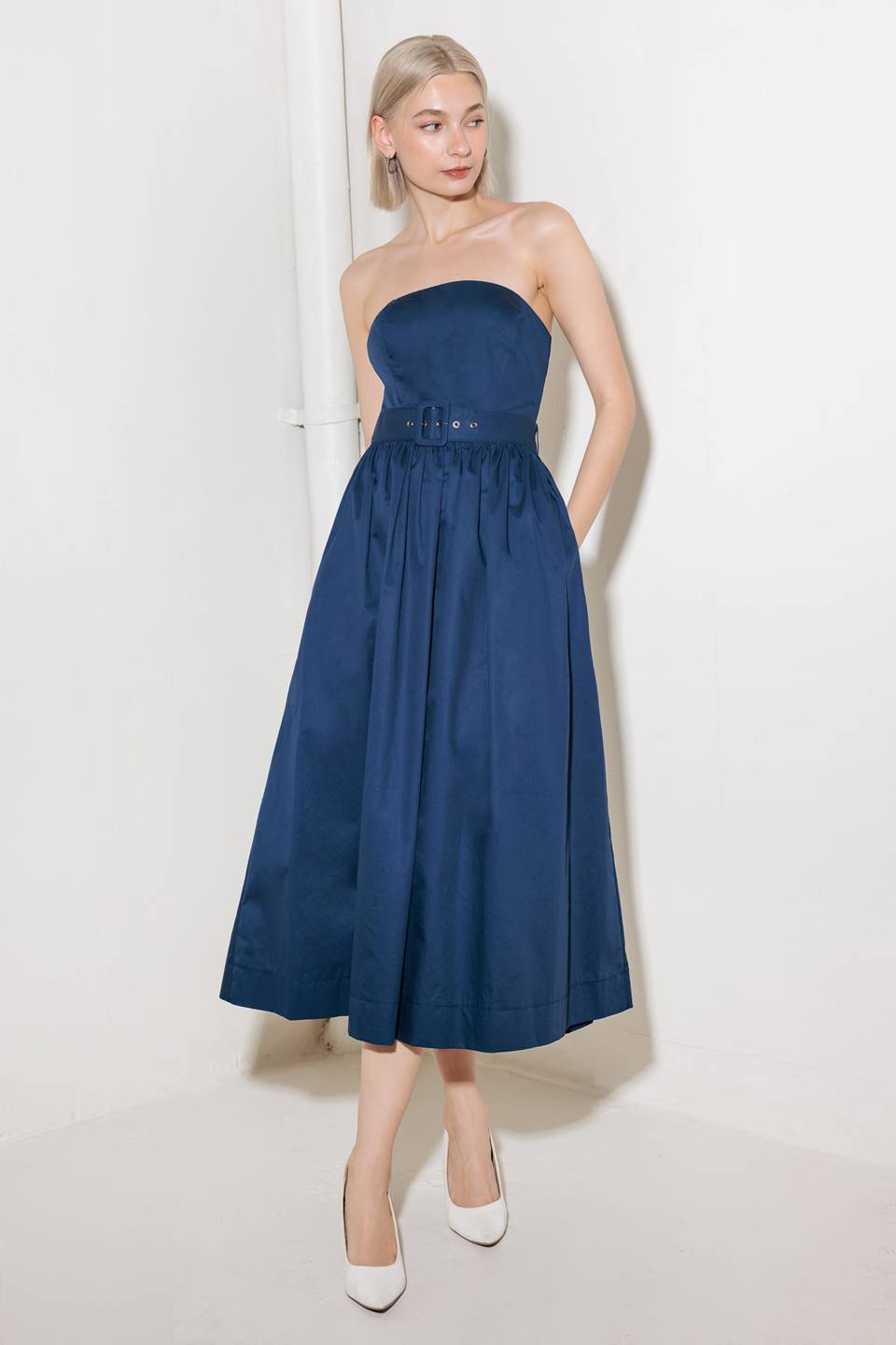 A strapless, solid navy, woven midi dress featuring self belt, full skirt and back zipper closure.