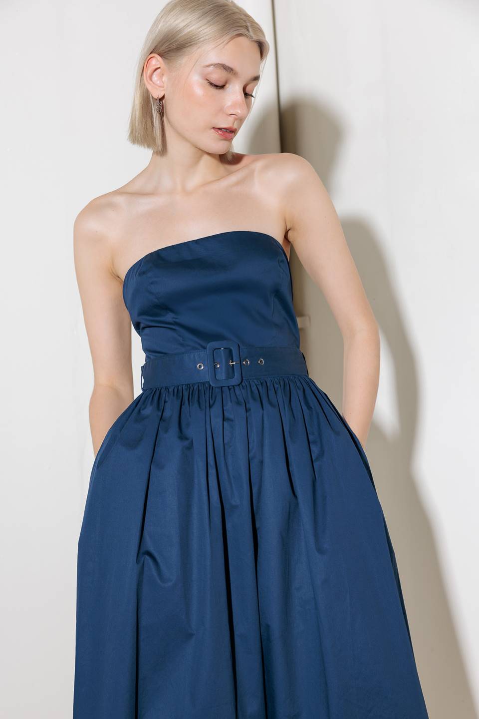 A strapless, solid navy, woven midi dress featuring self belt, full skirt and back zipper closure.