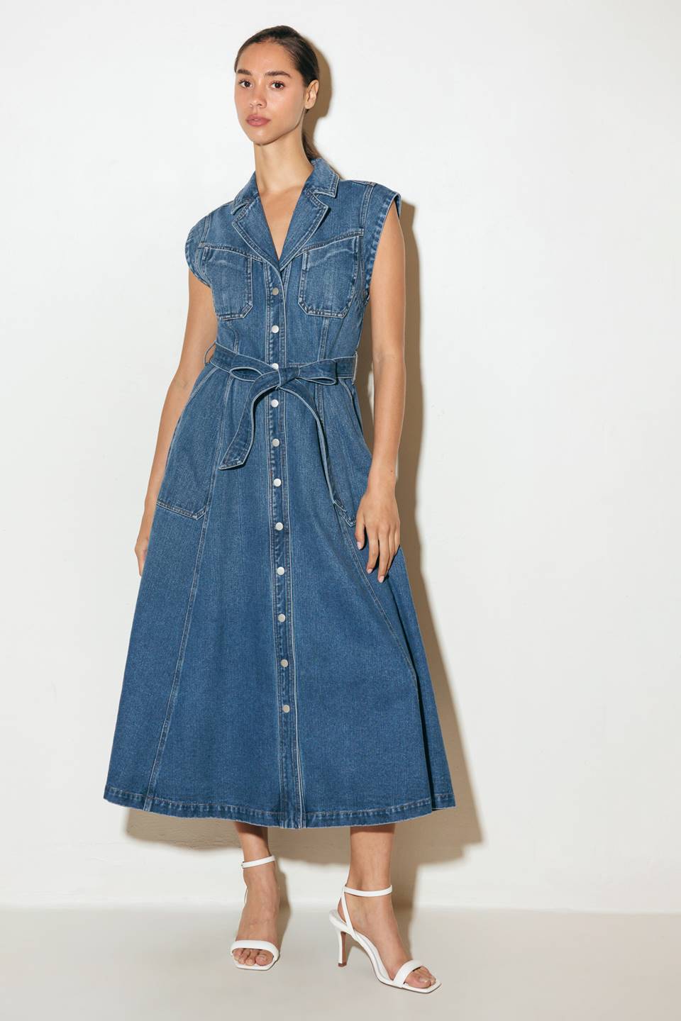 A washed denim midi dress featuring collar, short sleeve, front and side pockets,, button down and self sash tie.