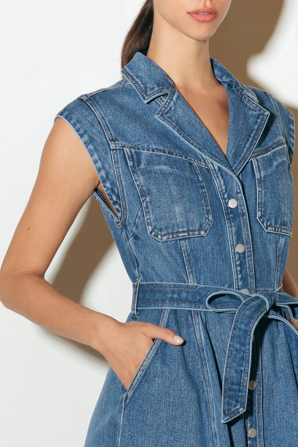 A washed denim midi dress featuring collar, short sleeve, front and side pockets,, button down and self sash tie.