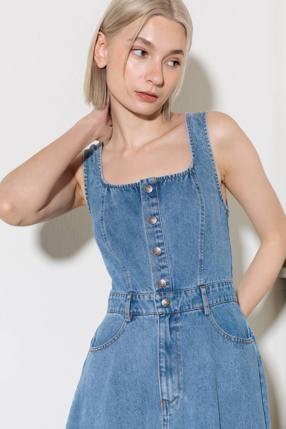 A washed denim midi dress featuring square neckline, sleeveless, front button down and zipper closure, side/back pockets and circle skirt.