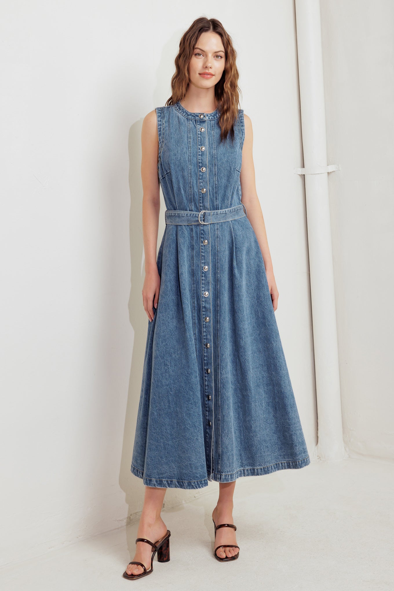 A washed denim midi dress featuring round neckline, sleeveless, button down, circle skirt and self belt