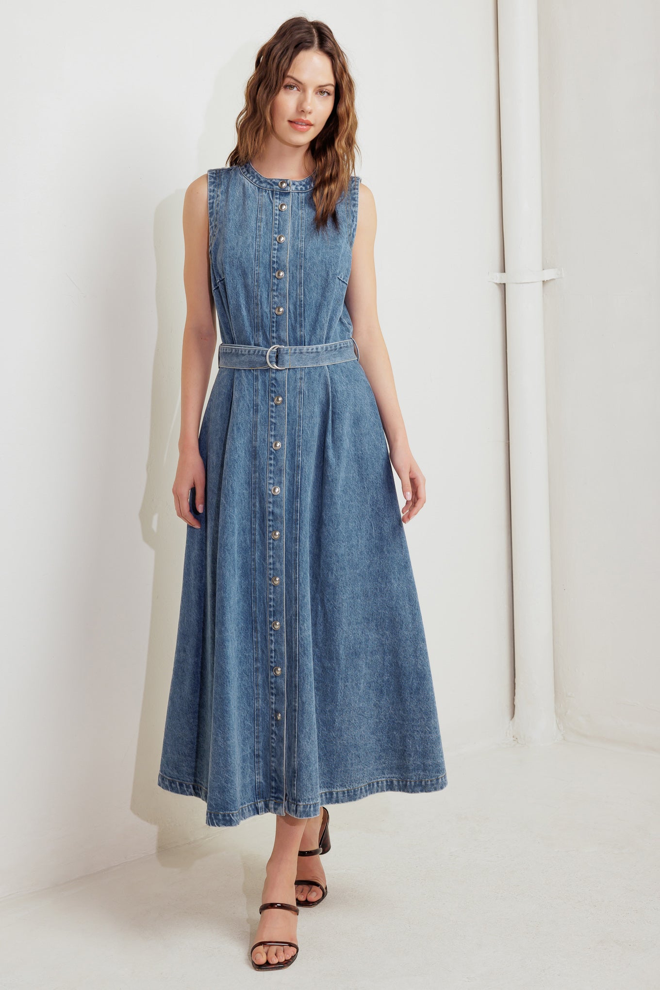 A washed denim midi dress featuring round neckline, sleeveless, button down, circle skirt and self belt