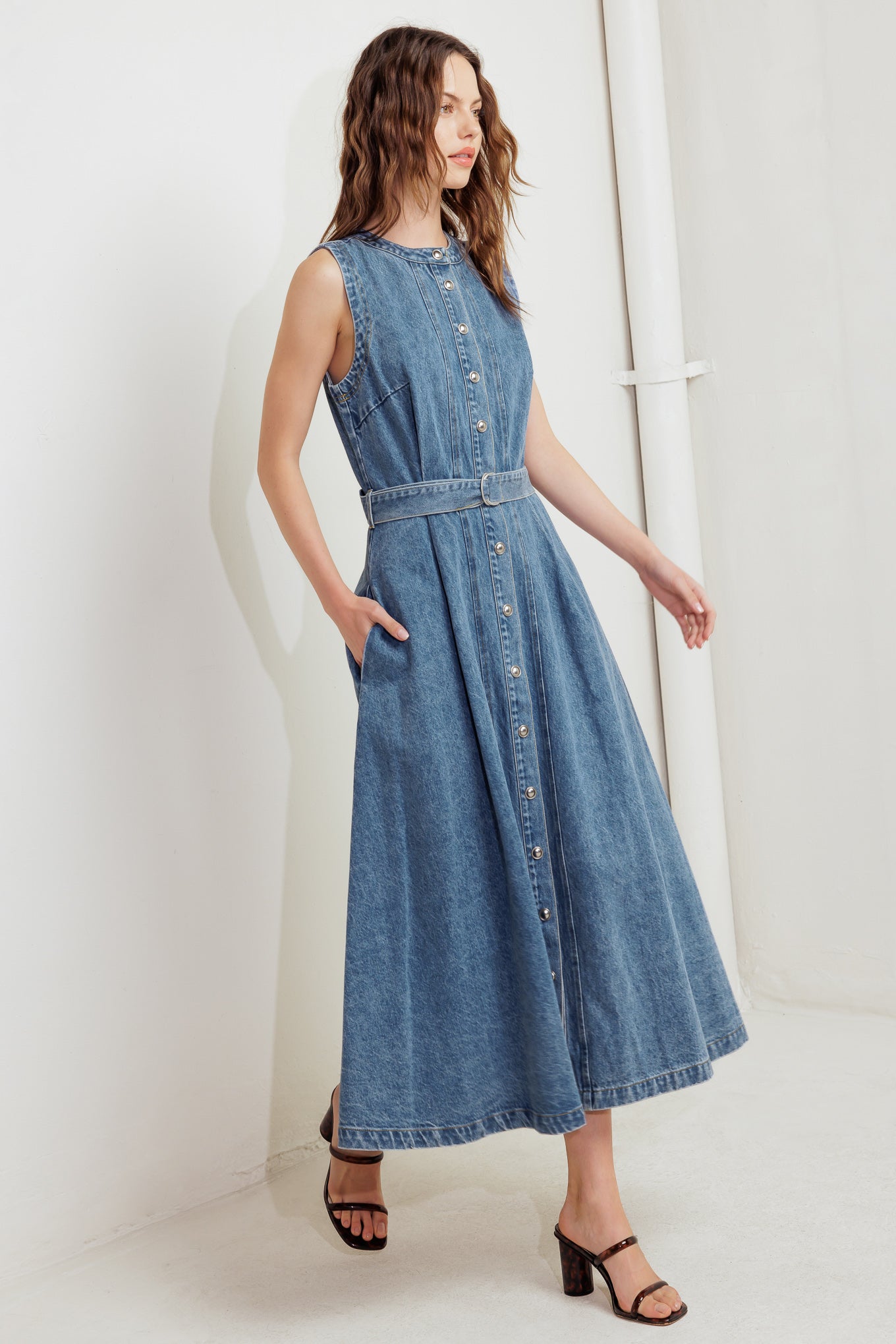 A washed denim midi dress featuring round neckline, sleeveless, button down, circle skirt and self belt