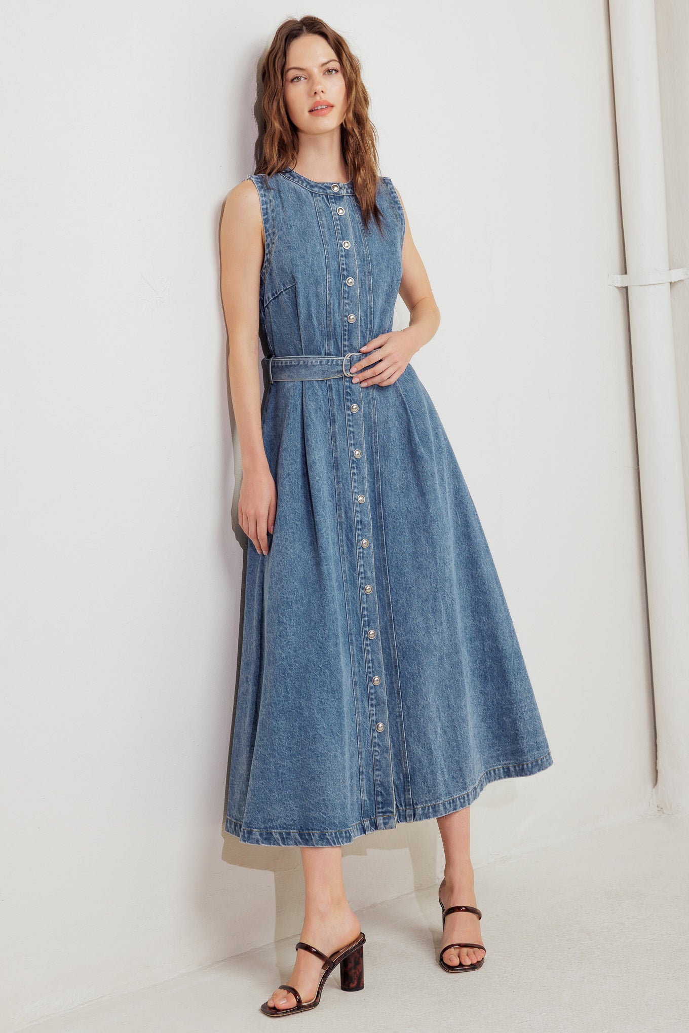 A washed denim midi dress featuring round neckline, sleeveless, button down, circle skirt and self belt