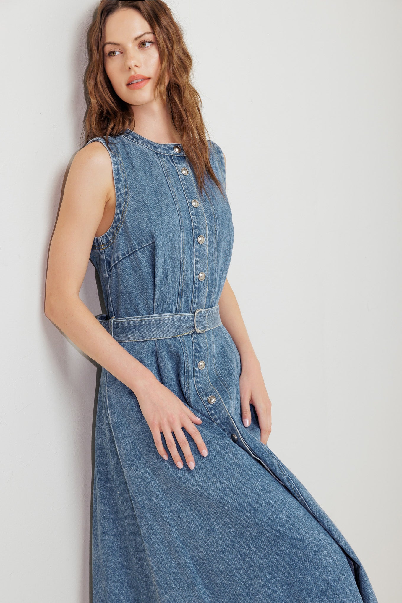 A washed denim midi dress featuring round neckline, sleeveless, button down, circle skirt and self belt