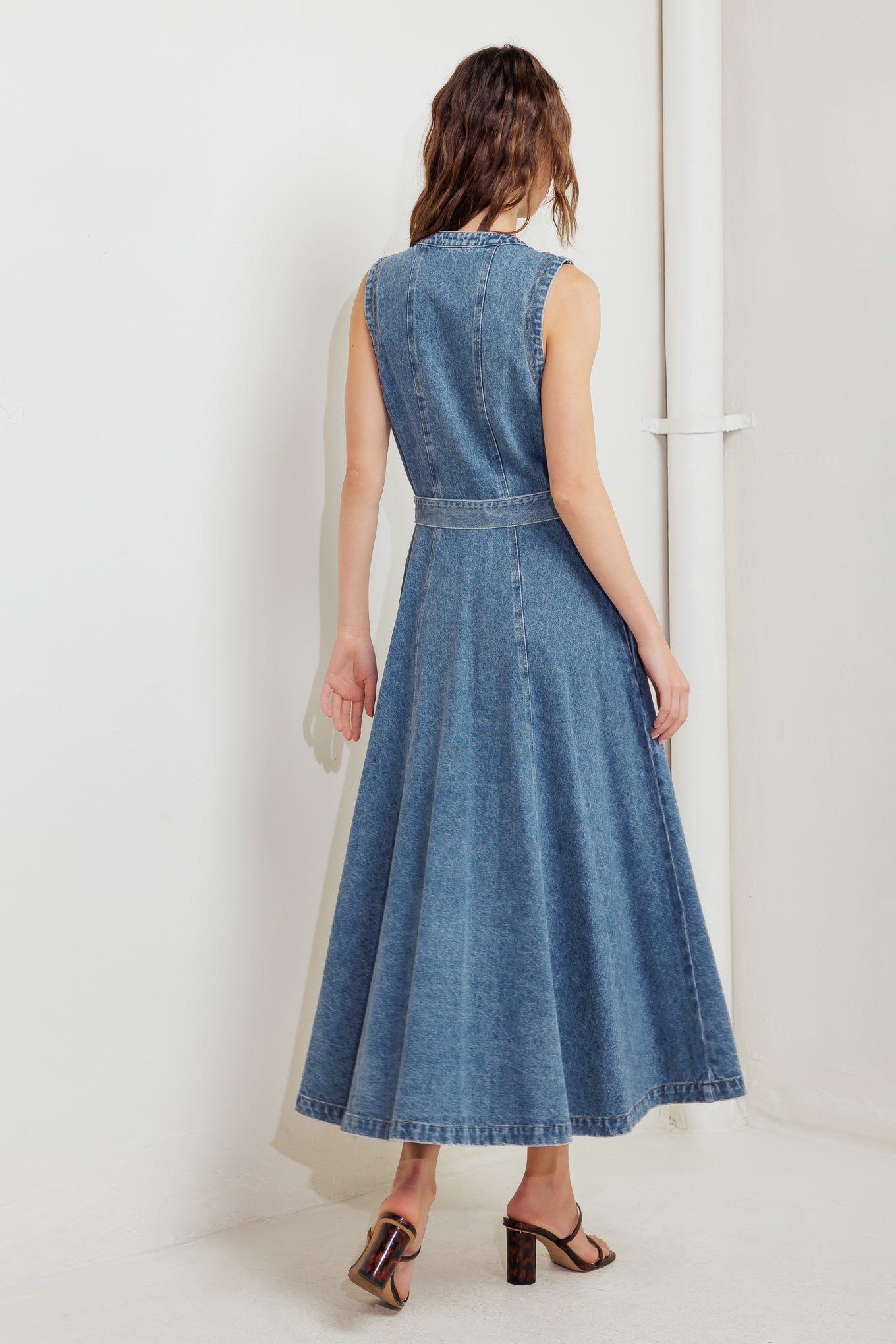 A washed denim midi dress featuring round neckline, sleeveless, button down, circle skirt and self belt