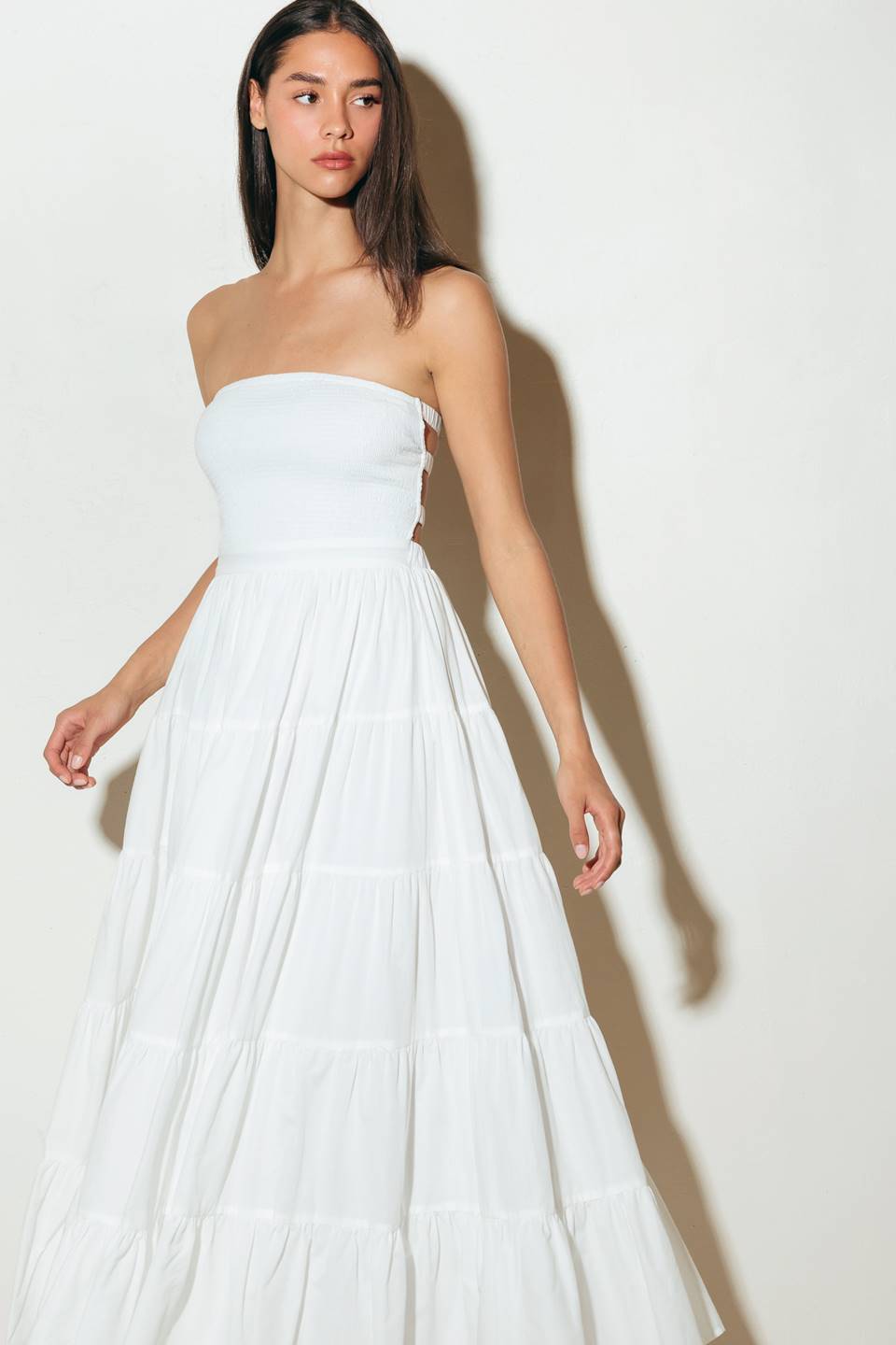 A solid woven midi dress featuring strapless, smocked bodice, tiered skirt and bare back with straps.
