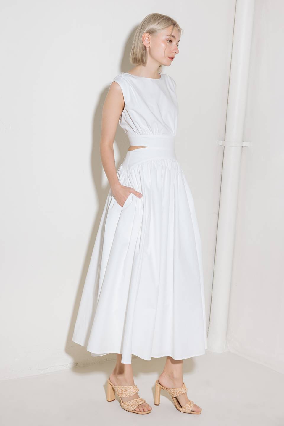 A solid woven midi dress featuring round neckline, sleeveless, side/back cut out, full skirt, side pocket and back zipper closure.