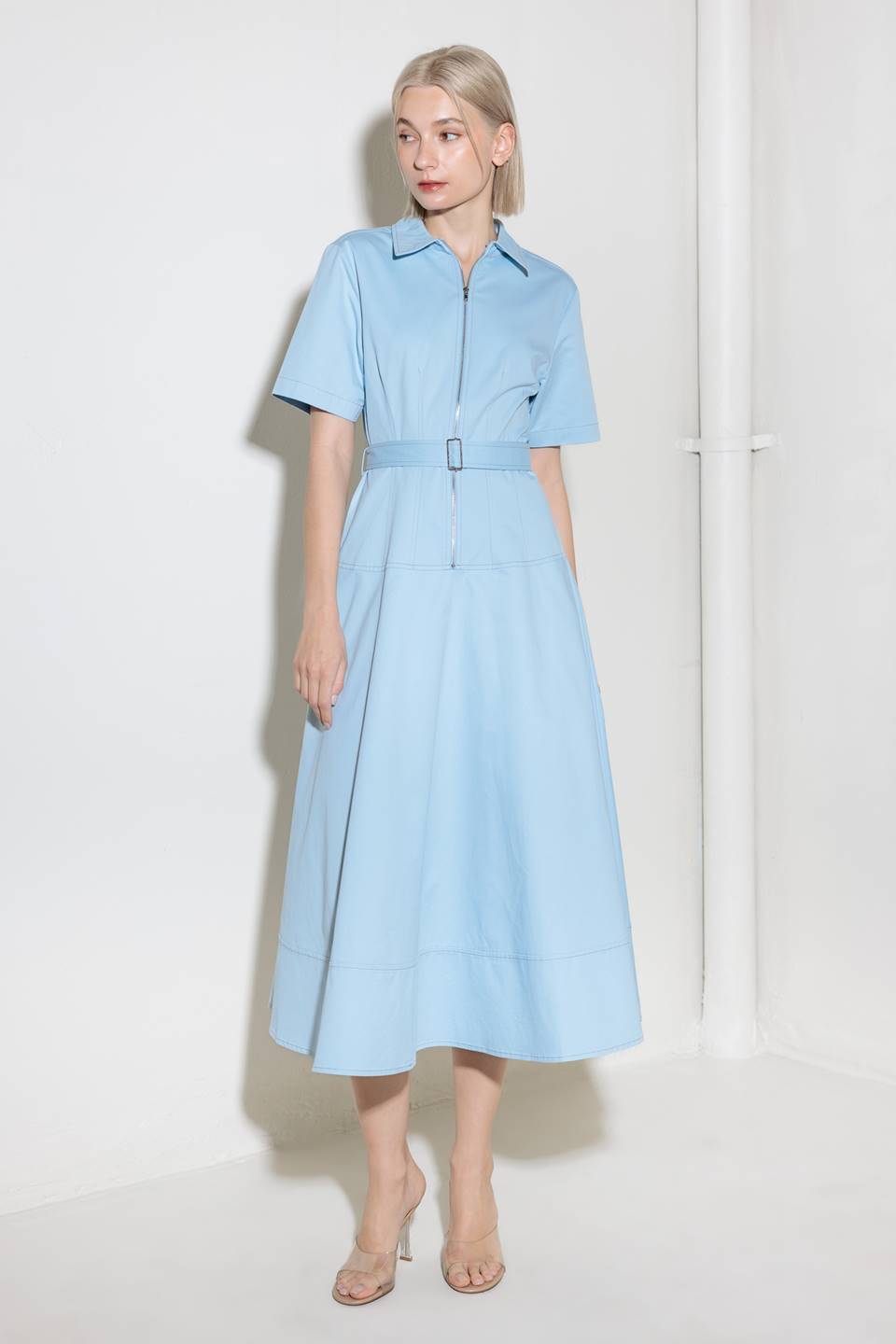 A solid woven shirt dress featuring collar, short sleeve, self belt, circle skirt and front zipper closure.