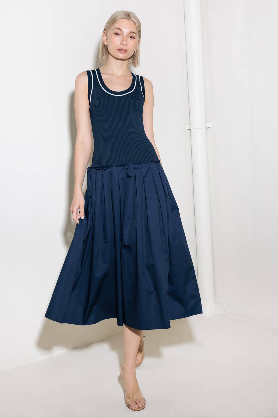 A ribbed sweater knit top and woven skirt combination dress featuring U neckline and sleeveless.