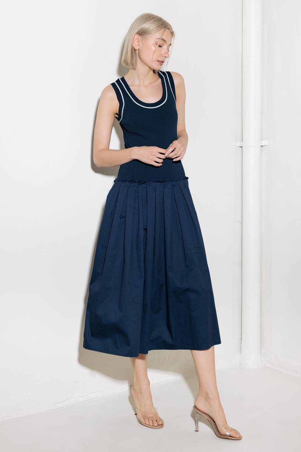 A ribbed sweater knit top and woven skirt combination dress featuring U neckline and sleeveless.