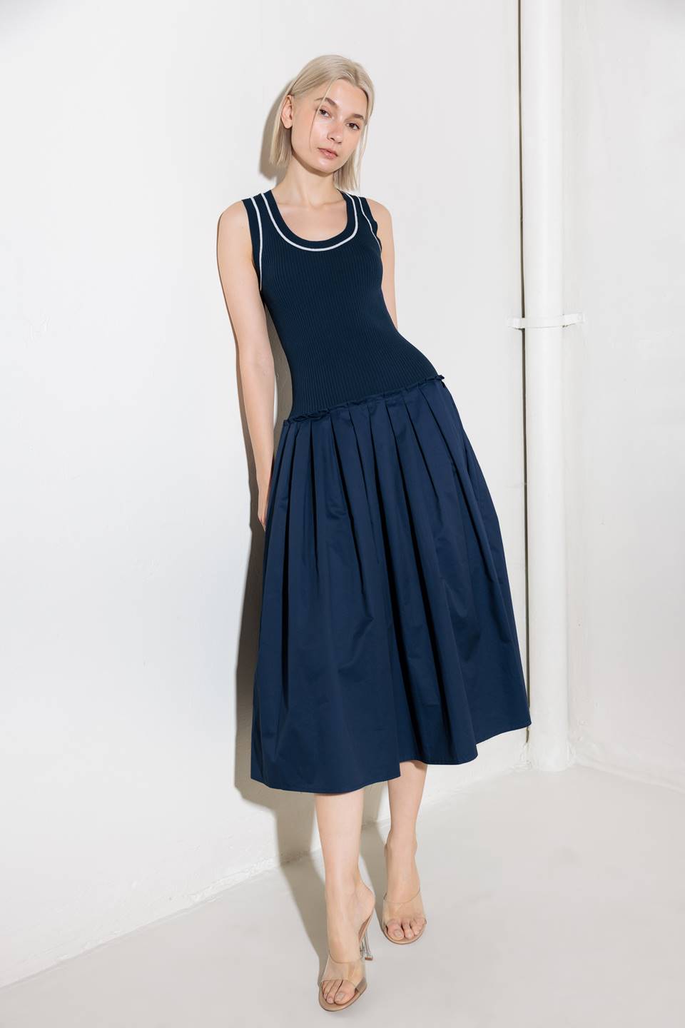 A ribbed sweater knit top and woven skirt combination dress featuring U neckline and sleeveless.