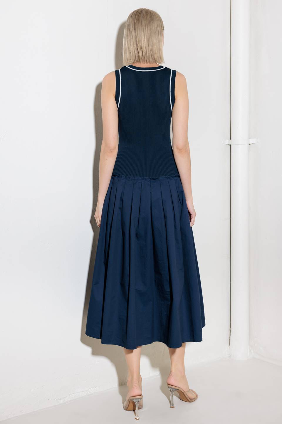 A ribbed sweater knit top and woven skirt combination dress featuring U neckline and sleeveless.