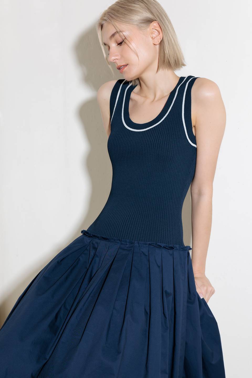 A ribbed sweater knit top and woven skirt combination dress featuring U neckline and sleeveless.