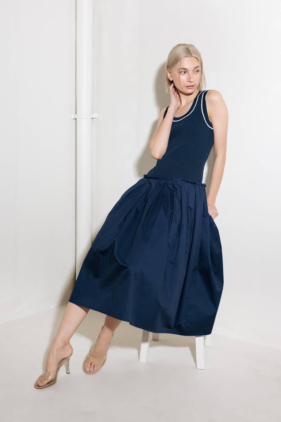 A ribbed sweater knit top and woven skirt combination dress featuring U neckline and sleeveless.