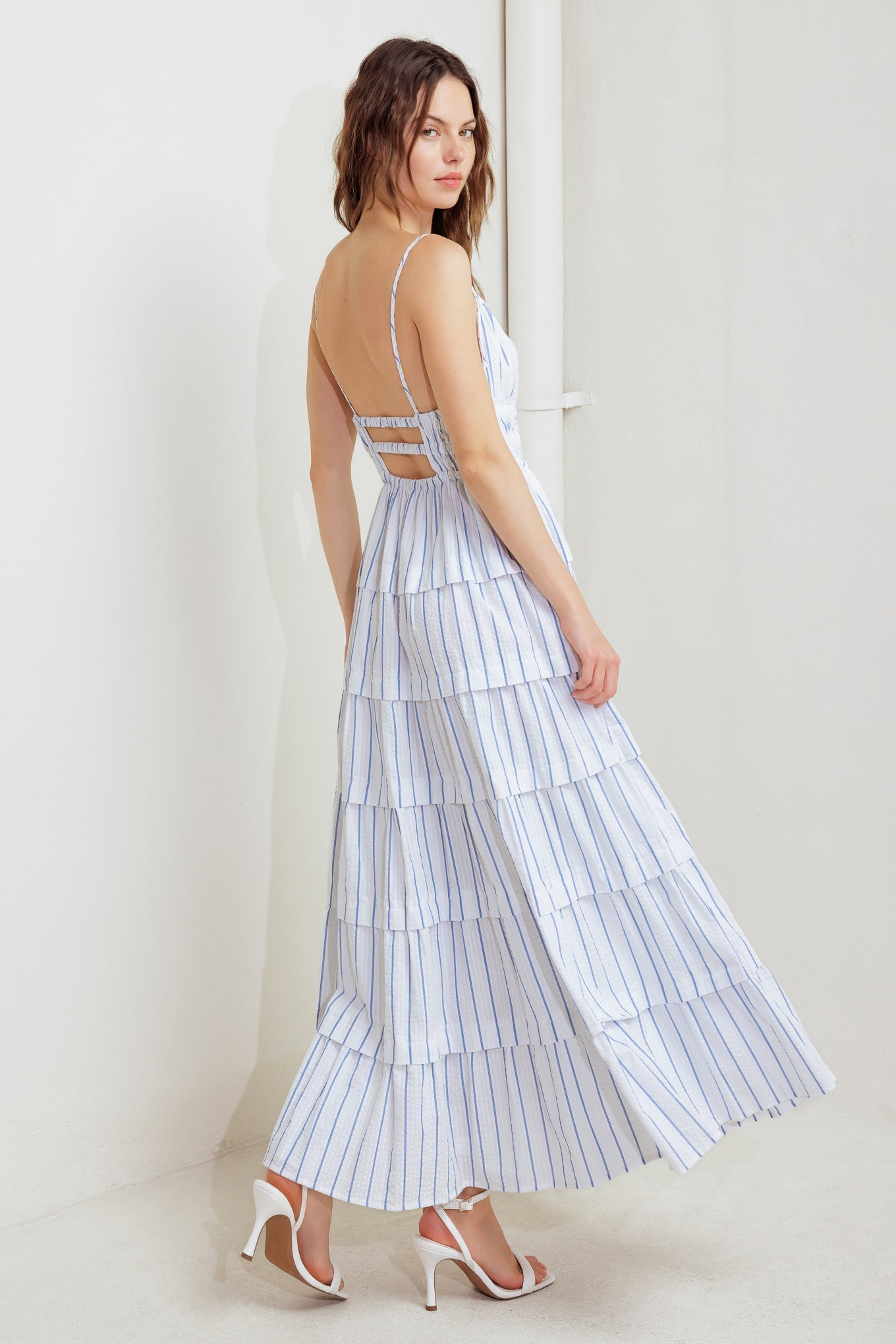 A striped woven midi dress featuring shirred top with front tie, smocked waist, tiered skirt and bare back with straps
