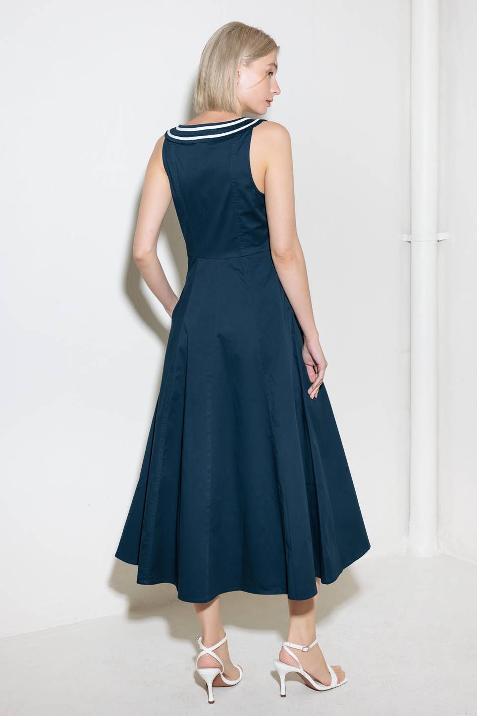 A solid woven midi dress fearturing U neckline, sleeveless, contrasting band and bow, button down and circle skirt.