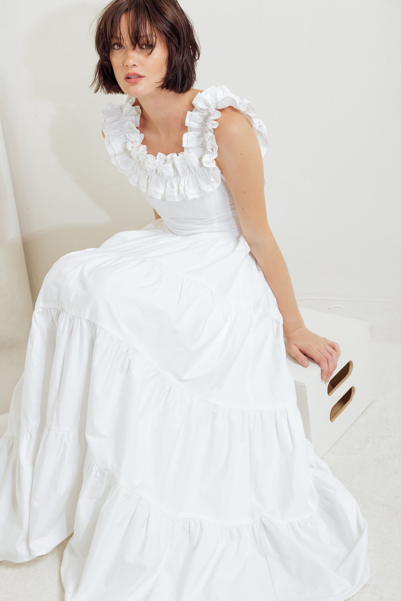 A solid woven midi dress featuring ruffled neckline, tiered skirt, smocked back bodice and tie closure
