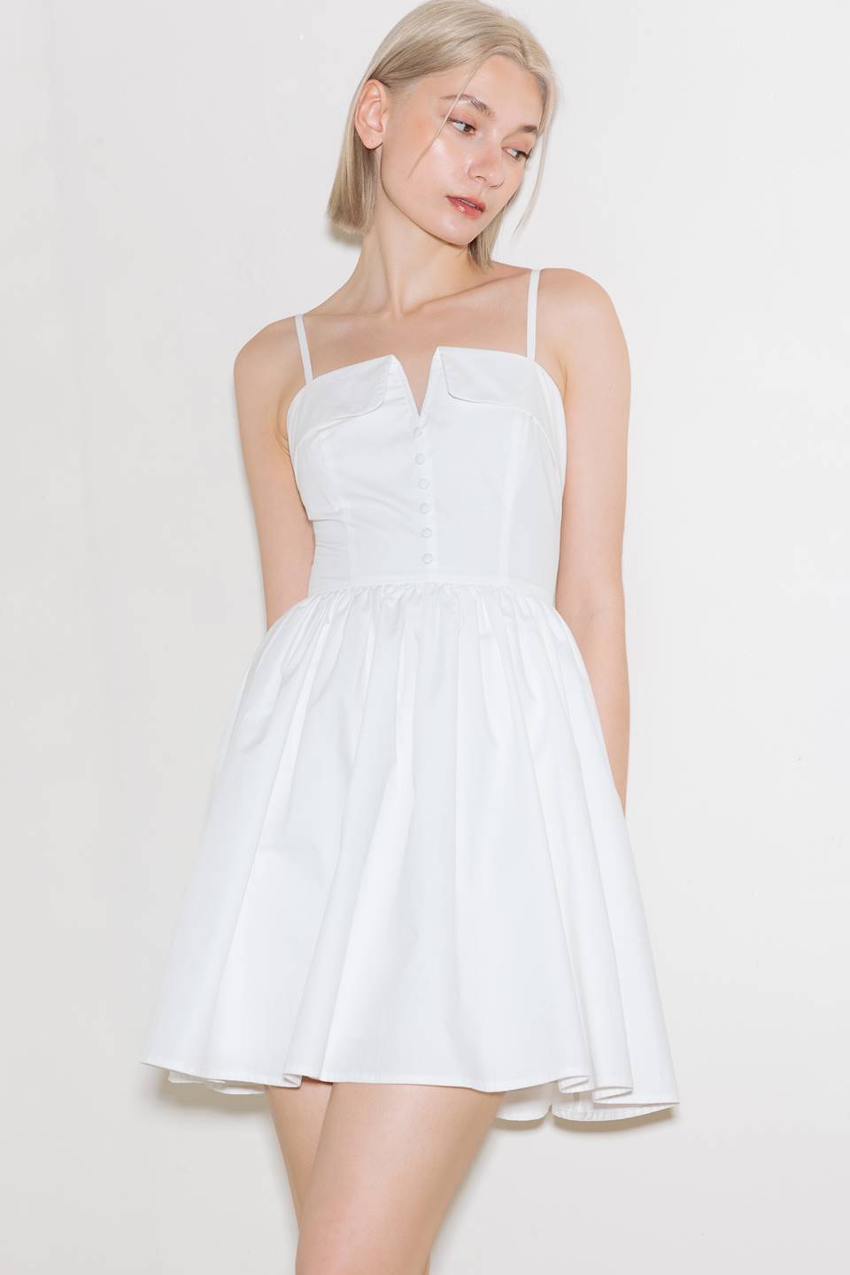 A solid woven mini dress featuring straight neckline with center V, straps, full skirt and back zipper closure.