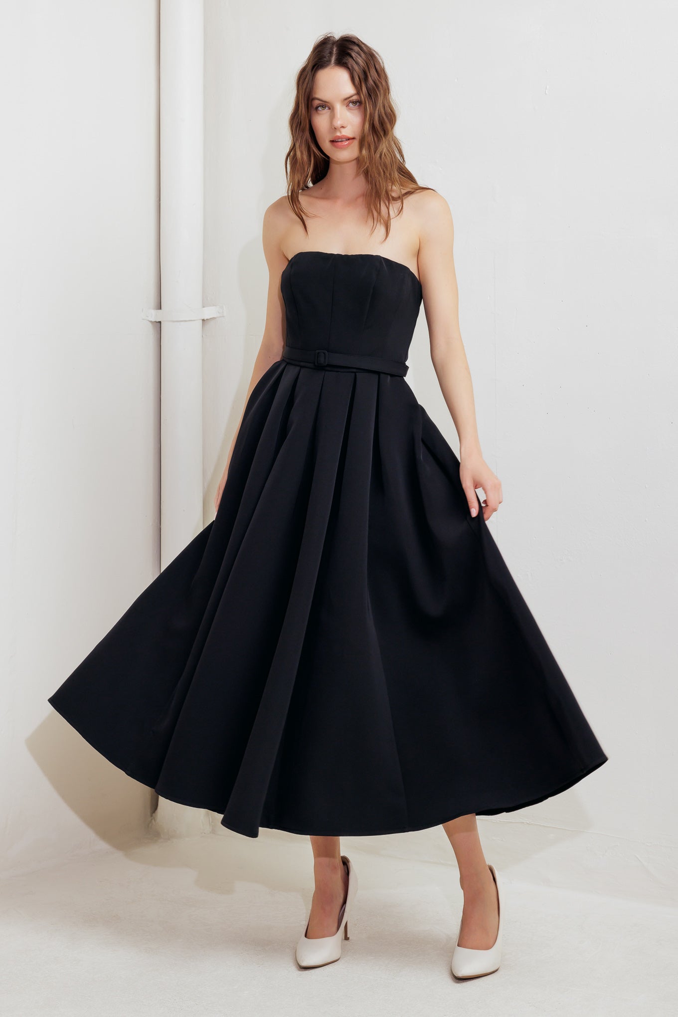 A solid woven midi dress featuring strapless straight neckline, self belt, full skirt and back zipper closure